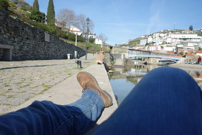 Low section of people on retaining wall against sky