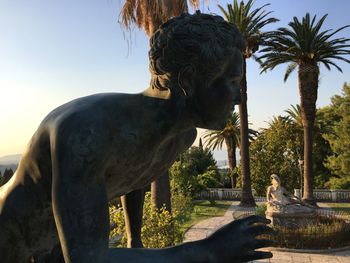 Statue by palm trees against sky