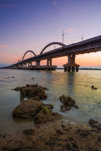 Bridge over sea against sky during sunset