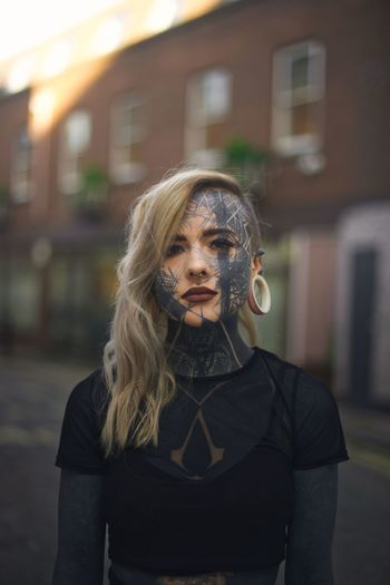 PORTRAIT OF YOUNG WOMAN STANDING IN FRONT OF BUILDING