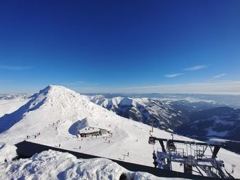 Aerial view of snowcapped mountains against blue sky during sunny day