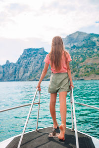 Rear view of woman looking at sea against mountain