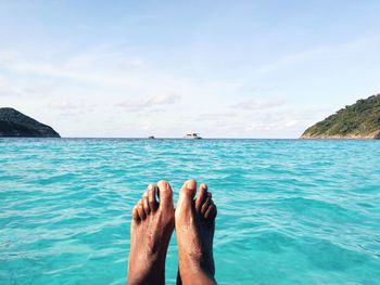 Low section of man by sea against sky