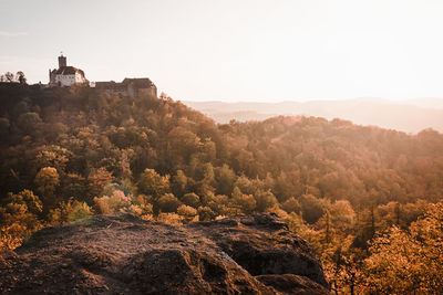 View of building on hill by forest against sky