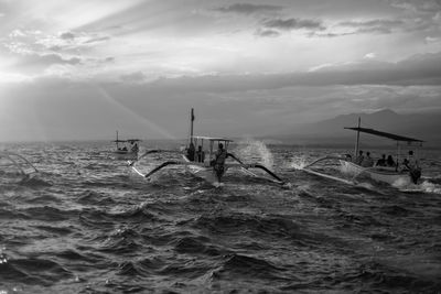 People on outrigger boats sailing in sea