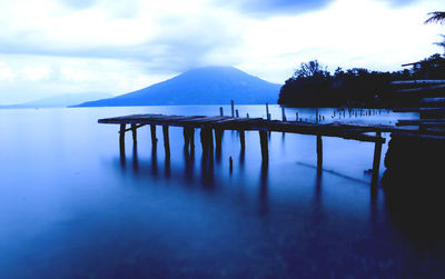 Jetty over calm lake against sky