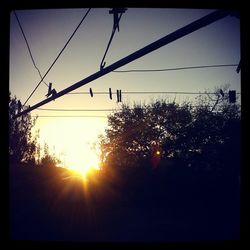 Low angle view of power lines at sunset