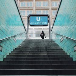 Rear view of woman walking on steps leading towards building at alexanderplatz