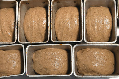 Dough for rye bread in metal molds. close-up preparation for baking in an artisan bakery