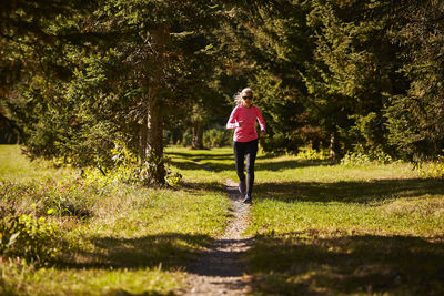 A woman trail running through the trees.