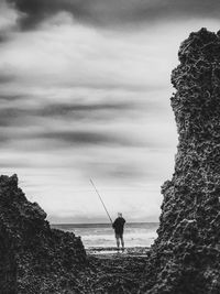 Man fishing in sea against sky