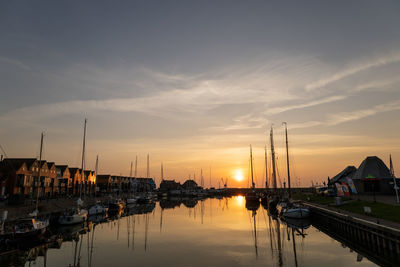 Sailboats moored at harbor during sunset