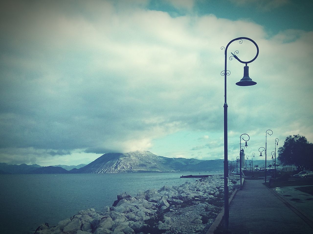 sky, street light, lighting equipment, tranquility, cloud - sky, tranquil scene, water, scenics, nature, beauty in nature, cloudy, mountain, sea, weather, cloud, lamp post, outdoors, overcast, idyllic, day