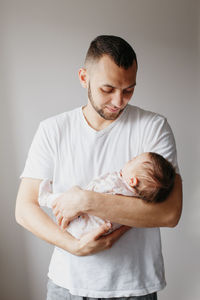 Father carrying baby daughter against white background