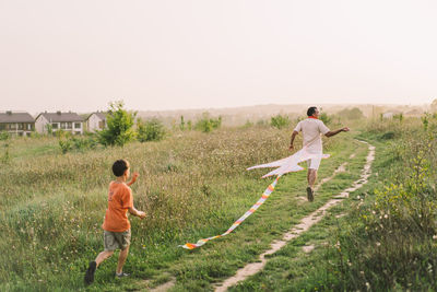 Happy family and children run on meadow with a kite in the summer on the nature.