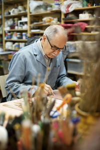 Senior artist carving bas relief while working at table in workshop