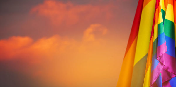 Low angle view of multi colored flags against sky during sunset