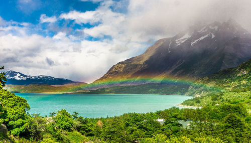 Scenic view of rainbow over land and mountains against sky