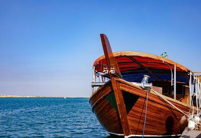 Boat moored in sea against clear blue sky