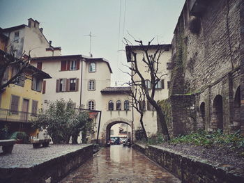 Wet alley amidst buildings in city during rainy season