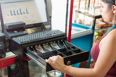 Latina woman looking disappointed at the cash register of her business to see how much money 