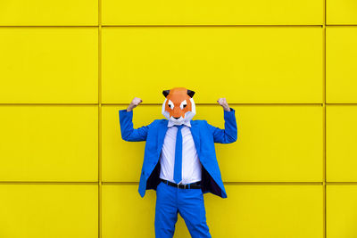 Full length of a man standing against yellow wall