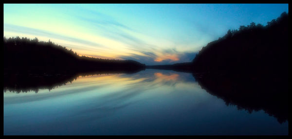 Reflection of trees in water at sunset