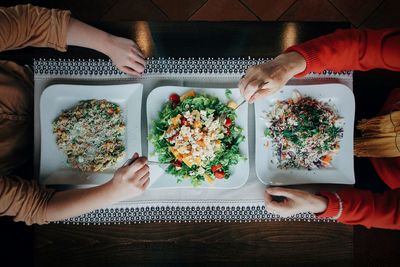 Cropped hands of friends having food at restaurant