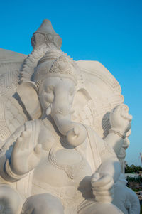 Low angle view of statue against building against blue sky