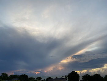 Low angle view of sunlight streaming through clouds