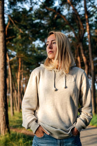 Portrait of a young blond woman walking in a pine forest at dawn.