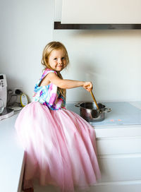 Little girl in elegant dress sitting on a table in the kitchen