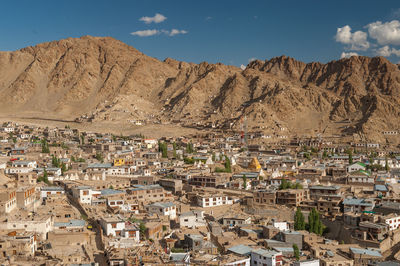 Aerial view of townscape and mountains against sky