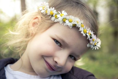 Close-up portrait of smiling girl wearing flowers on hair