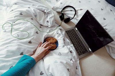 Cropped hand of woman eating food on bed