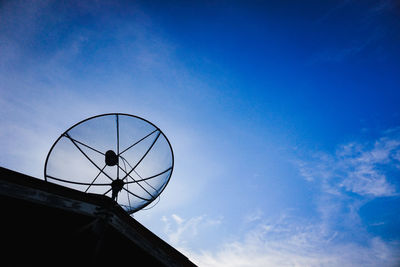 Low angle view of silhouette telephone against blue sky