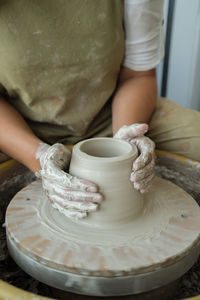 Midsection of woman making pottery in workshop