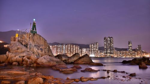 View of city by sea against sky at night