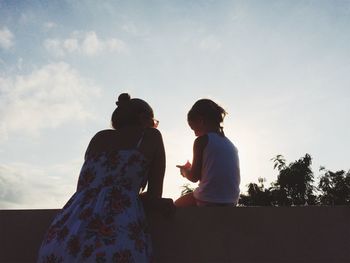 Low angle view of mother and daughter against sky