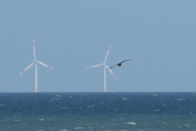 Wind turbines in sea against sky