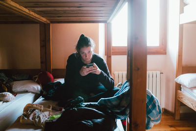 Portrait of woman using phone while sitting on bed