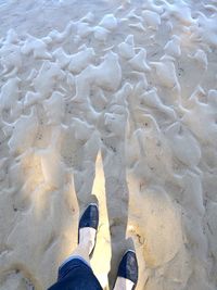 Low section of man standing on sand at beach