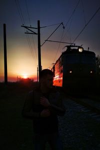 Man standing on street against sky during sunset