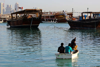 Rear view of men in boat at harbor