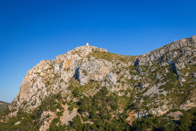 Low angle view of rock formation against clear blue sky