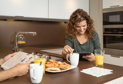 Woman with digital tablet sitting by husband in house