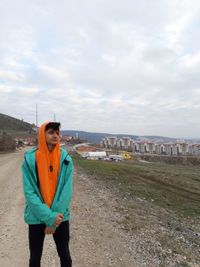 Teenage boy standing on road against sky