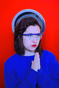 Young woman with hands clasped against orange background