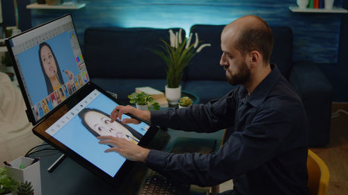 Side view of man using laptop at table