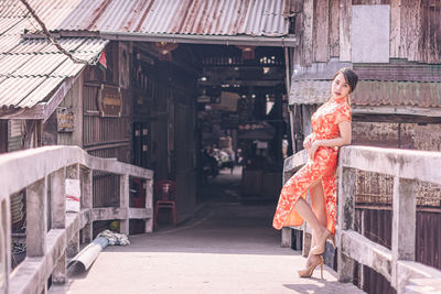 Portrait of woman in red dress standing on bridge